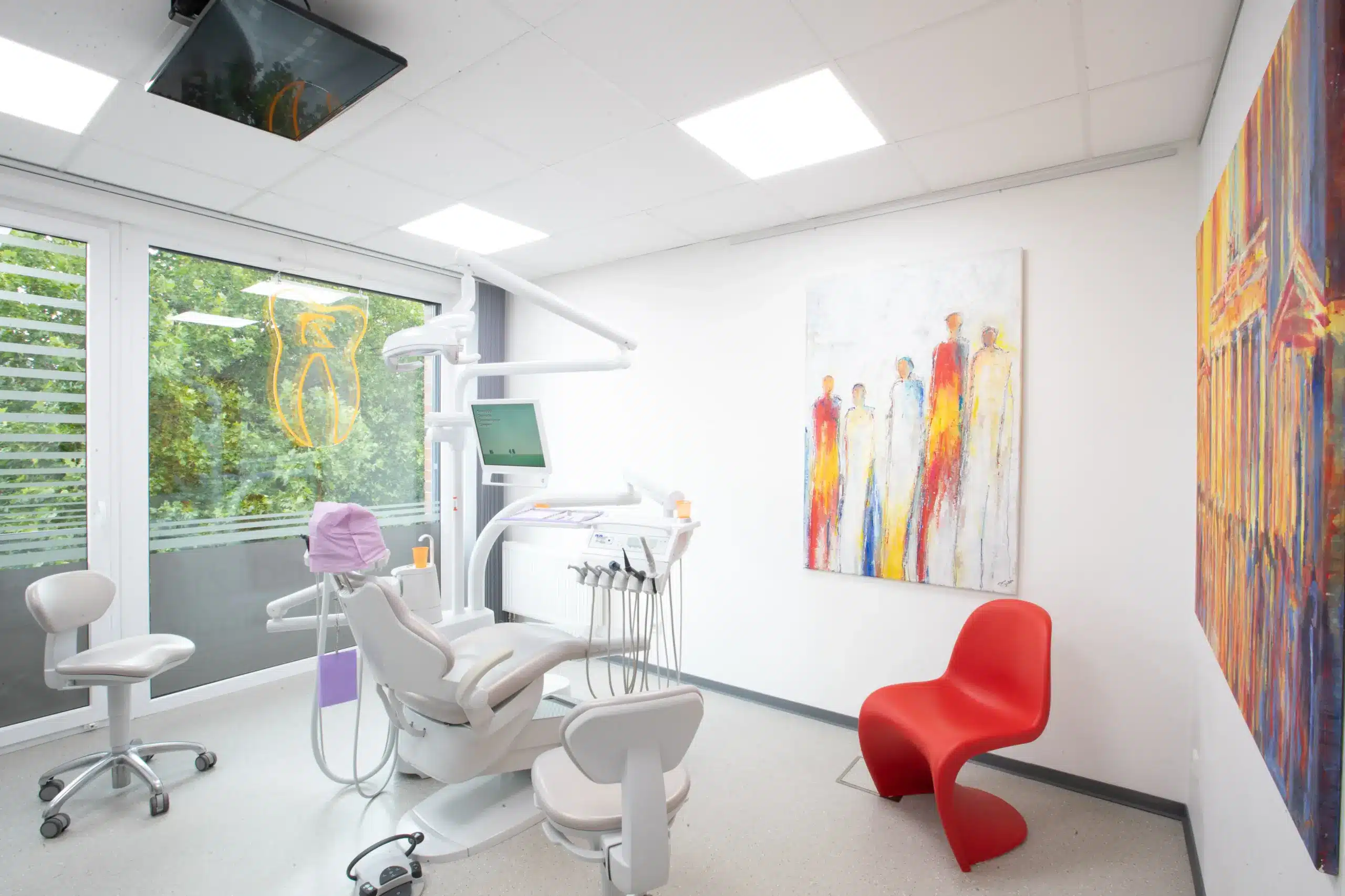 Lichtdurchflutetes Behandlungszimmer der Zahnarztpraxis Dr. Menninger in Pinneberg mit bodentiefem Fenster und rotem Designstuhl